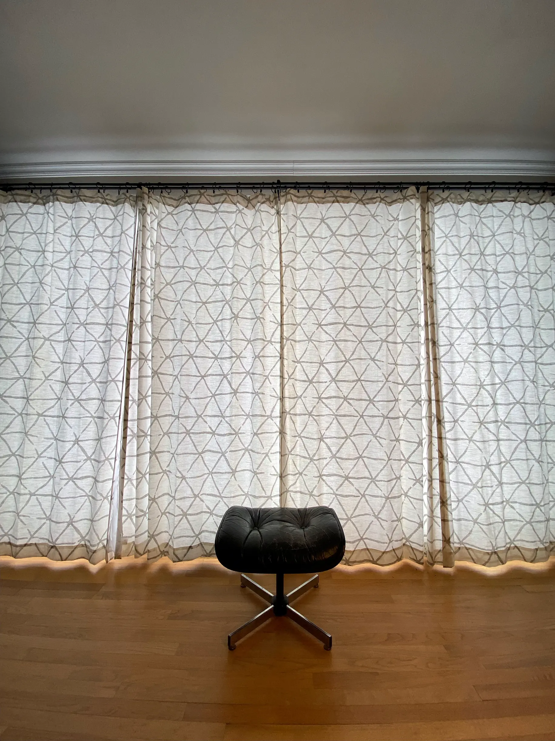A behind-the-scenes shot at the simple set used for the Desire music video, featuring an empty footrest on a wooden floor in front of drawn curtains.