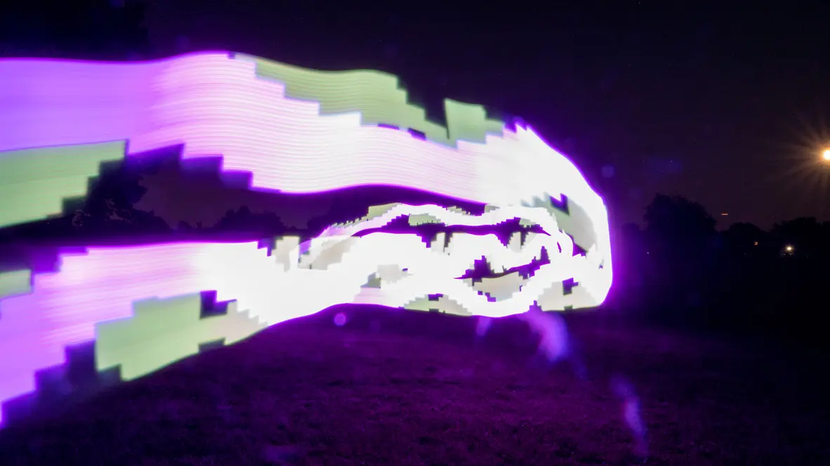 Experimental photograph with psychedelic, colorful shapes in a field outdoors at night.