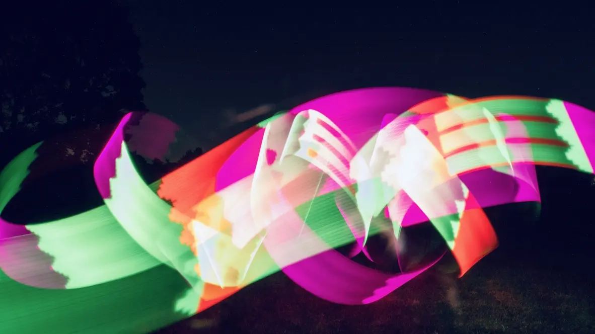 Experimental photograph with psychedelic, colorful shapes in a field outdoors at night.