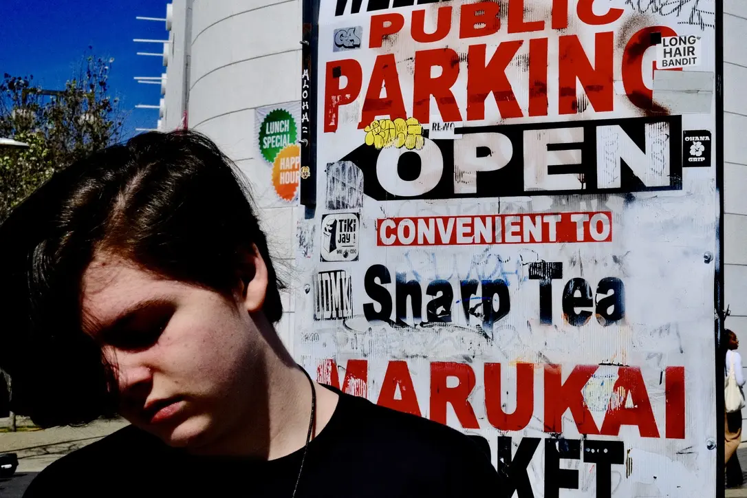 Extreme metal musician Miles Plumb in front of a distressed sign in Little Tokyo, Los Angeles.